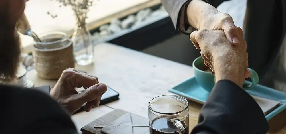 How to Settle Credit Card Debt for Less (Do It Yourself) — Business agreement handshake at coffee shop