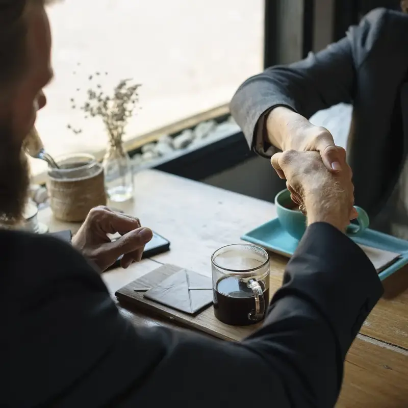 How to Settle Credit Card Debt for Less (Do It Yourself) — Business agreement handshake at coffee shop